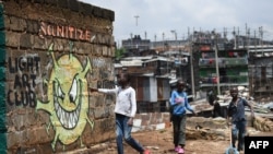 A young boy reads out the message from an informational mural warning people about the risk of COVID-19 in a slum in Nairobi, Kenya, April 22, 2020. 