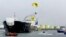 Một thành viên của Greenpeace trên chiếc dù lượn mang theo tấm biểu ngữ viết 'No Arctic Oil' (tạm dịch: Không khoan dầu ở Bắc Băng Dương) bay trên đầu chiếc tàu chờ dầu của Nga Mikhail Ulyanov ở cảng Rotterdam. '