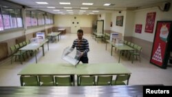 A polling official arranges a ballot box at a polling station ahead of Spain's general election in Madrid, Spain, Dec. 18, 2015. 