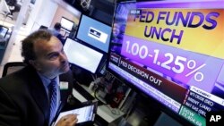 A trader watches a television screen on the floor of the New York Stock Exchange showing the rate decision of the U.S. Federal Reserve, in New York, Nov. 1, 2017.