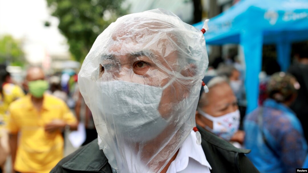 Seorang lelaki mengenakan penutup wajah untuk melindungi dari virus corona saat ia mengantri untuk mengajukan formulir untuk meminta bantuan keuangan tiga bulan dari pemerintah di depan Kementerian Keuangan di Bangkok, Thailand. (Foto: Reuters)