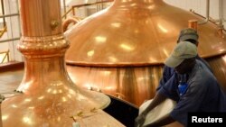 Wafanyakazi wakimimina vitu vya kutengenezea pombe kwenye birika kwenye kampuni ya Nile Brewery.