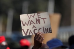 FILE - A person holds a placard as supporters of the Economic Freedom Fighters (EFF) march to demand a rollout of coronavirus disease (COVID-19) vaccines, in Pretoria, South Africa, June 25, 2021.