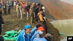 Warga menunggu sementara tim penyelamat mencari para pekerja yang hilang di sebuah tambang batu giok di Hpakant, negara bagian Kachin, Myanmar utara (22/12).