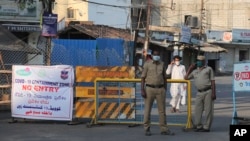 Policemen stand guard near a barricade at a containment zone to prevent outsiders from entering during lockdown in Hyderabad, India, April 10, 2020. 