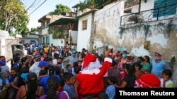 Un hombre disfrazado de Santa Claus, de la ONG "Santa en las calles", saluda a los vecinos antes de repartir alimentos y donar ropa, en un barrio de bajos recursos de Guarenas, al este de Caracas, Venezuela el 19 de diciembre de 2020.