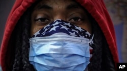 FILE - An African American subway rider wears a mask and a bandana to protect himself against the coronavirus in New York City, April 7, 2020. 