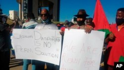 People hold banners as they stage a protest in Windhoek, Namibia, May 28, 2021.