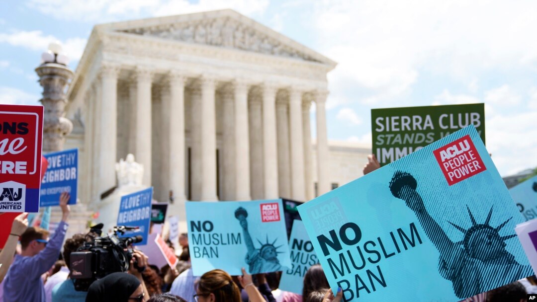 FILE - Protesters hold up signs outside the the Supreme Court in Washington, June 26, 2018.