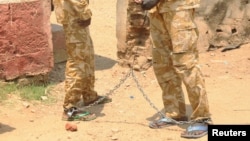 FILE - South Sudanese soldiers suspected of beating and raping civilians are chained together at the presidential guard unit, within the Sudan People's Liberation Army headquarters, after their arrest in Juba, March 3, 2017. 