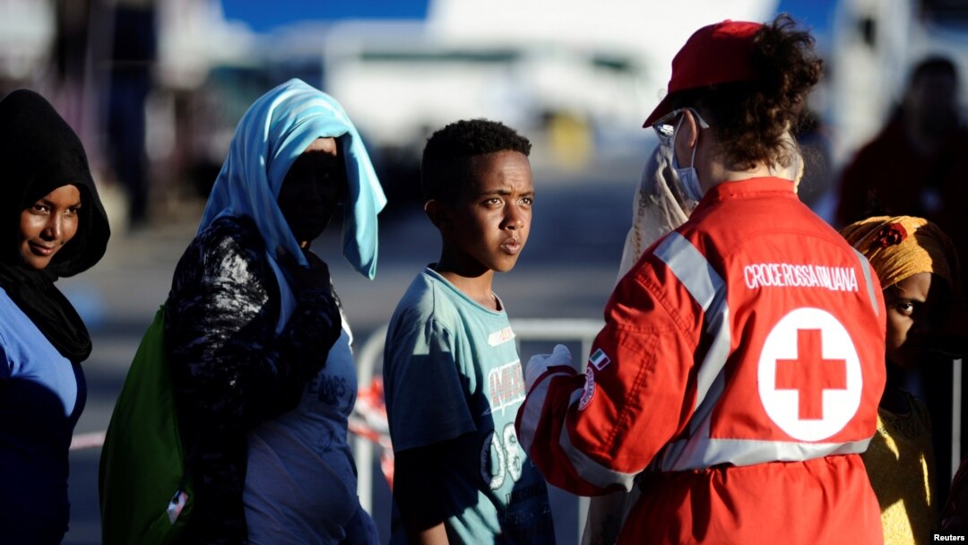 Migrants stand in a line in front of Red Cross member after disembarking from the Italian navy ship Borsini in the Sicilian harbor of Palermo, southern Italy, July 20, 2016.