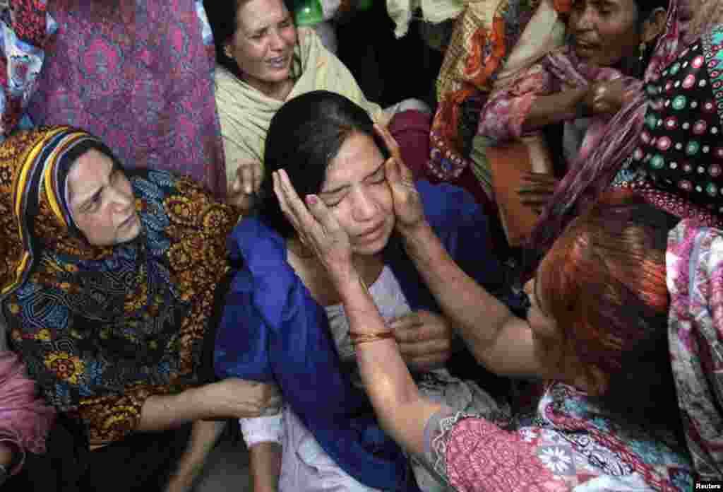 Family members comfort a woman mourns the death of a relative, who was killed in a blast outside a public park on Sunday, during funeral in Lahore, Pakistan, March 28, 2016. 