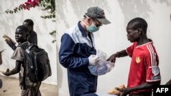 Un travailleur du Village Pilote distribue de l'eau et des sandwichs aux enfants des rues de Dakar, le 10 avril 2020.