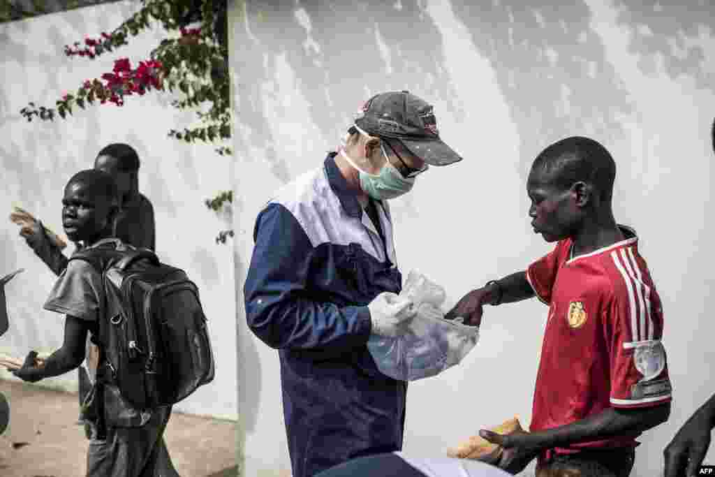 Un travailleur du Village Pilote distribue de l&#39;eau et des sandwichs aux enfants des rues de Dakar, le 10 avril 2020.