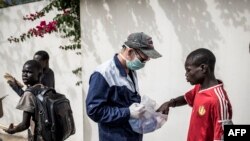 Un travailleur du Village Pilote distribue de l'eau et des sandwichs aux enfants des rues de Dakar, le 10 avril 2020, pendant le confinement.