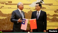 Malaysia's Prime Minister Najib Razak (L) speaks to China's Premier Li Keqiang during a signing ceremony at the Great Hall of the People in Beijing, May 29, 2014.