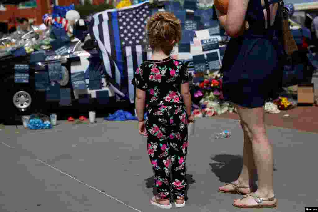 A young girl is among those visiting a makeshift memorial at Dallas police headquarters two days after a lone gunman ambushed and killed five officers at a protest decrying police shootings of black men, July 9, 2016. 