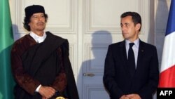 Le président français Nicolas Sarkozy (R) et le leader libyen Mouammar Kadhafi posent lors de la signature de 10 milliards d'euros de contrats commerciaux, à Paris, le 10 décembre 2007.