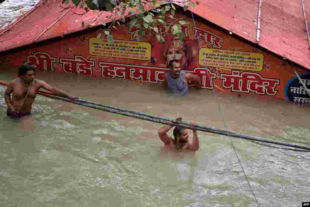 People wade through outside a submerged Hanuman temple as the water levels of the Ganges and Yamuna rivers rise in Allahabad, India, Aug. 7, 2021.