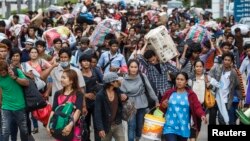 Cambodian migrant workers carry their belongings as they walk to cross the border at Aranyaprathet in Sa Kaew, June 15, 2014. 