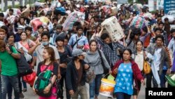 Cambodian migrant workers carry their belongings as they walk to cross the border at Aranyaprathet in Sa Kaew, June 15, 2014. 