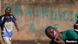 Protesters march past graffiti reading "No to power for life," referring to President Blaise Compaore, in Ouagadougou, Burkina Faso, October 28, 2014. Police fired tear gas at rock-throwing protesters after tens of thousands of people marched through Burk