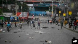 La gente corre después de que estallaron los enfrentamientos durante una protesta contra el aumento de los precios del combustible y para exigir que el primer ministro haitiano Ariel Henry renuncie, en Puerto Príncipe, Haití, el 16 de septiembre de 2022.