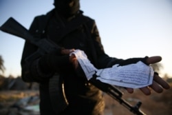 FILE - A member of the Libyan security forces displays part of a document in Arabic describing weaponry that was found at the site of U.S. airstrikes on an Islamic State camp near the western city of Sabratha, Libya, Feb. 20, 2016.