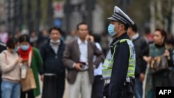 A police officer wearing a face mask monitors pedestrian traffic along a street in Shanghai on October 28, 2020.