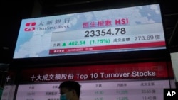 A man wearing face mask walks past a bank electronic board showing the Hong Kong share index at Hong Kong Stock Exchange Tuesday, May 26, 2020.