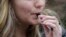 FILE - An unidentified 15-year-old high school student uses a vaping device near the school's campus in Cambridge, Massachusetts, April 11, 2018. 