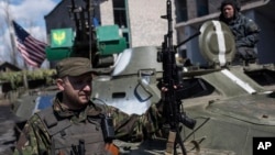 A Ukrainian serviceman stands near an armored vehicle, with a U.S. flag, in Shyrokyne, eastern Ukraine, April 15, 2015. 