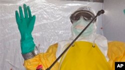 A health worker is sprayed with disinfectant after he worked with patients that contracted the Ebola virus, at a clinic in Monrovia, Liberia, Sept. 8, 2014. 