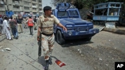 A paramilitary soldier walks past a police armored personnel carrier, which was hit by a bomb attack in Karachi, Pakistan, April 5, 2012.