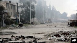 En esta foto divulgada por la agencia oficial de noticias siria SANA se ve una calle dañada por enfrentamientos fuerzas del gobierno sirio y rebeldes cerca de la plaza Abbassiyin, en el este de Damasco, Siria, el lunes, 20 de marzo, de 2017.