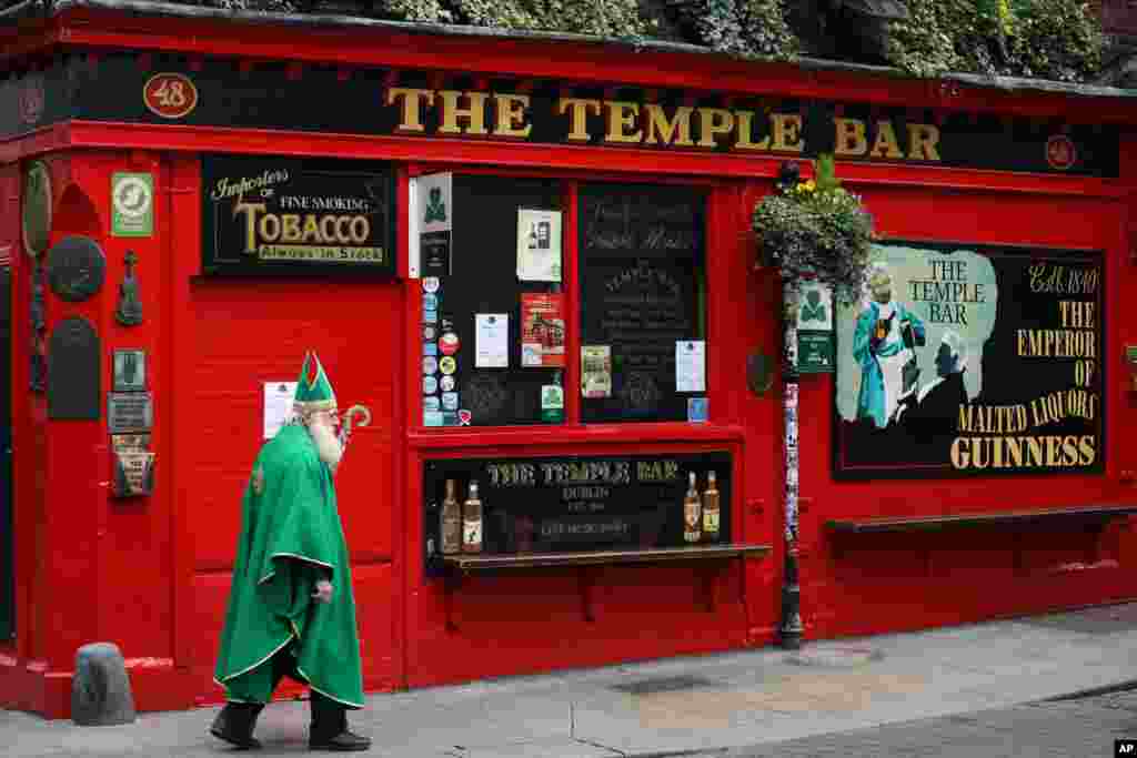 A man dressed as St. Patrick walks past a closed Temple bar in Dublin city center, Ireland.
