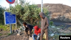 De jeunes migrants attendent la distribution de nourriture près du camp de réfugiés de Calais, en France, le 23 août 2017.