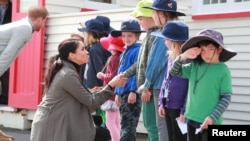 Prince Harry, Duke of Sussex, with Meghan Markle, Duchess of Sussex, meet schoolboy Joe Young, right, and other children outside the Maranui Cafe in Wellington, New Zealand, Oct. 29, 2018.