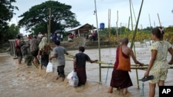 Local residents wade through flooded water at a broken bridge, in Naypyitaw, Myanmar, Sept. 17, 2024. 