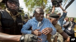 Uganda's main opposition leader Kizza Besigye, center, is arrested by police and thrown into the back of a blacked-out police van which whisked him away and was later seen at a rural police station, outside his home in Kasangati, Uganda, Feb. 22, 2016. 