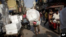 An Indian labourer carries a load through a busy street on a hot afternoon in New Delhi, India, Friday, May 13, 2016. 