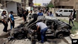 Warga Baghdad mengelilingi sebuah mobil yang hancur akibat ledakan bom (Foto: dok). Dua serangan bunuh diri terpisah di kota Mosul menewaskan dua polisi dan satu tentara serta melukai tujuh lainnya termasuk dua warga sipil, Senin (24/6).