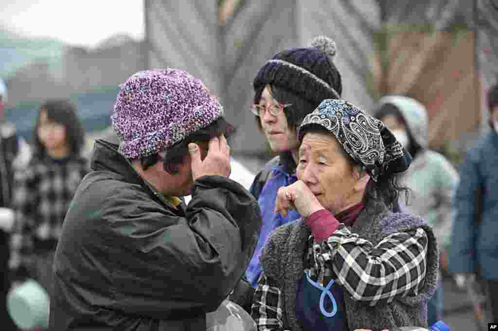 Two women cry with one another while waiting for water at a distribution point in Ofunato five days after the devastating earthquake and ensuing tsunami, March 16, 2011. (AFP)