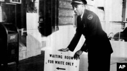 Police Lt. Beavers Armstrong places a segregation sign in front of the Illinois Central Railroad Jan. 9, 1956, after the railroad removed segregation signs from waiting rooms. 