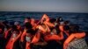 ARCHIVO - Una mujer sostiene a un bebé de 3 meses mientras migrantes y refugiados de diferentes nacionalidades africanas esperan ayuda en un bote de goma abarrotado, el 12 de febrero de 2021, en aguas internacionales del Mar Mediterráneo a 122 millas de la costa de Libia.