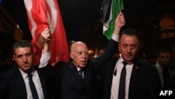 A handout picture provided by the Tunisian Presidency Press Service shows Tunisia's President Kais Saied, center, celebrating with supporters in the capital of Tunis after being re-elected.