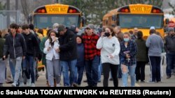 Orang tua dengan anak-anak mereka pergi meninggalkan tempat parkir Meijer setelah insiden penembakan di Oxford High School di Oxford, Michigan, AS, 30 November 2021. (Foto: Eric Seals-USA TODAY NETWORK via REUTERS)