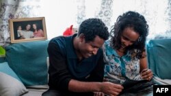 Getahun Fetana (L) and his wife Emebet Melaku (R), married taking advantage of a chance run-in during Timkat, the Ethiopian Orthodox celebration of epiphany, looks at photographs in their home in the city of Gondar, Ethiopia, January 18, 2020.