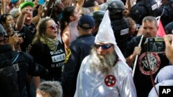 FILE - A Ku Klux Klan white supremacist is escorted by police during a KKK and counter-rally in Charlottesville, Virginia, July 8, 2017.
