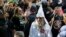 FILE - A Ku Klux Klan white supremacist is escorted by police during a KKK and counter-rally in Charlottesville, Virginia, July 8, 2017.